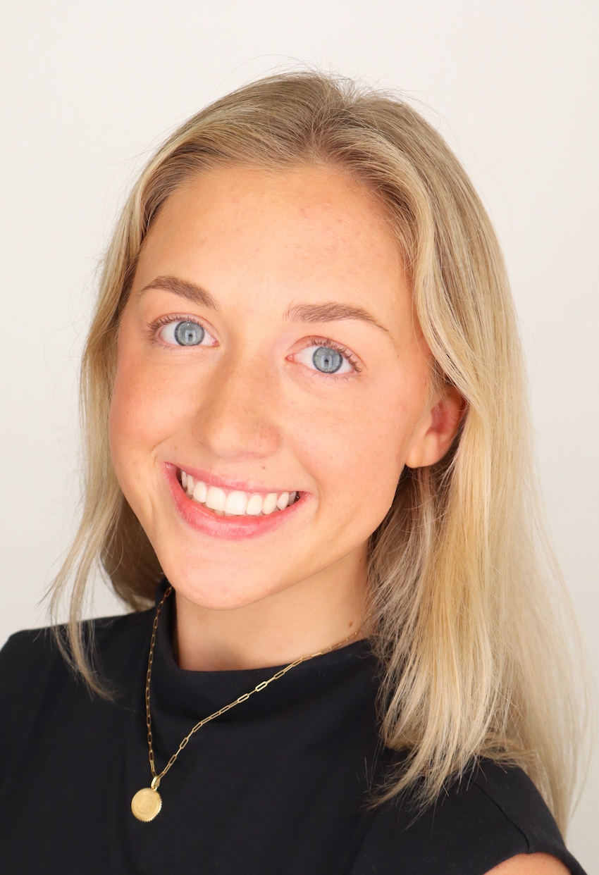 A woman wearing a black sweater and a red shirt is smiling for the camera.