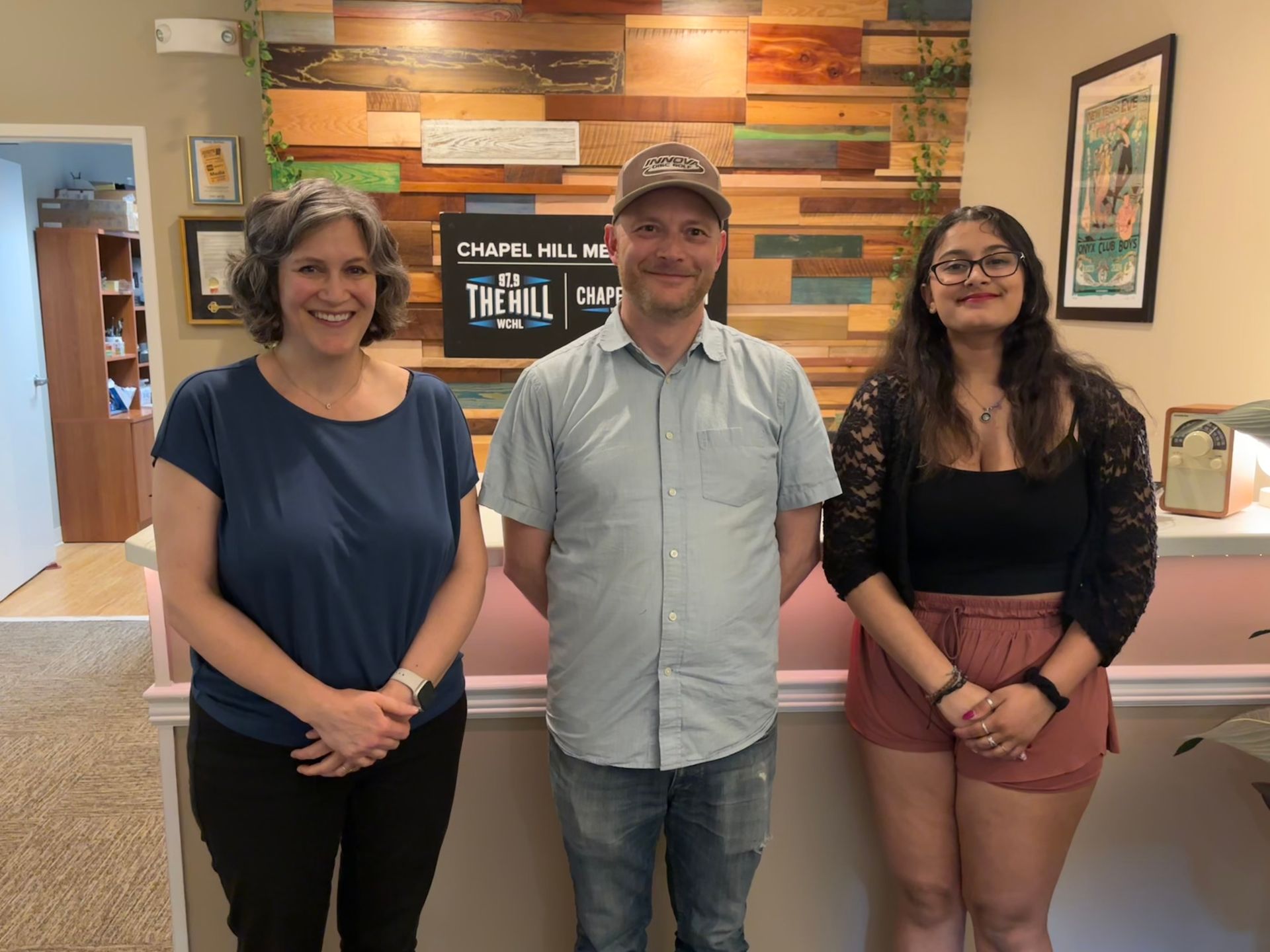 Three people standing in front of a sign that says trail