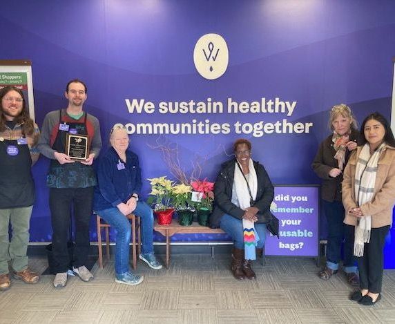 A group of people standing in front of a wall that says we sustain healthy communities together
