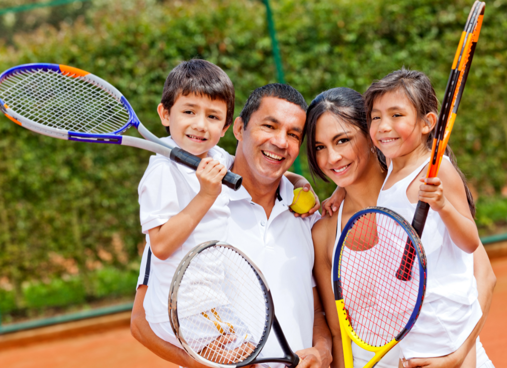 A family holding tennis rackets on a tennis court