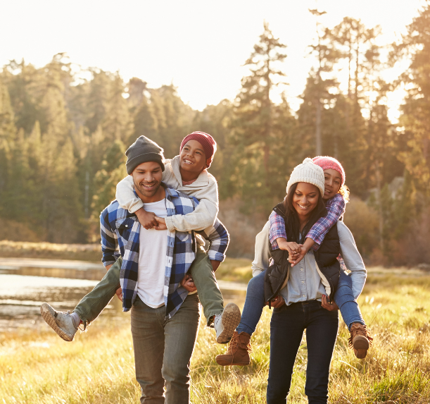 A group of people carrying children on their shoulders in a field