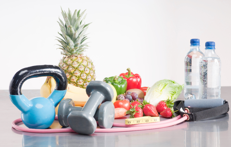 A bunch of fruits and vegetables on a table with a kettlebell and dumbbells