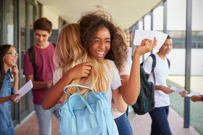 A group of students are hugging each other in a hallway.