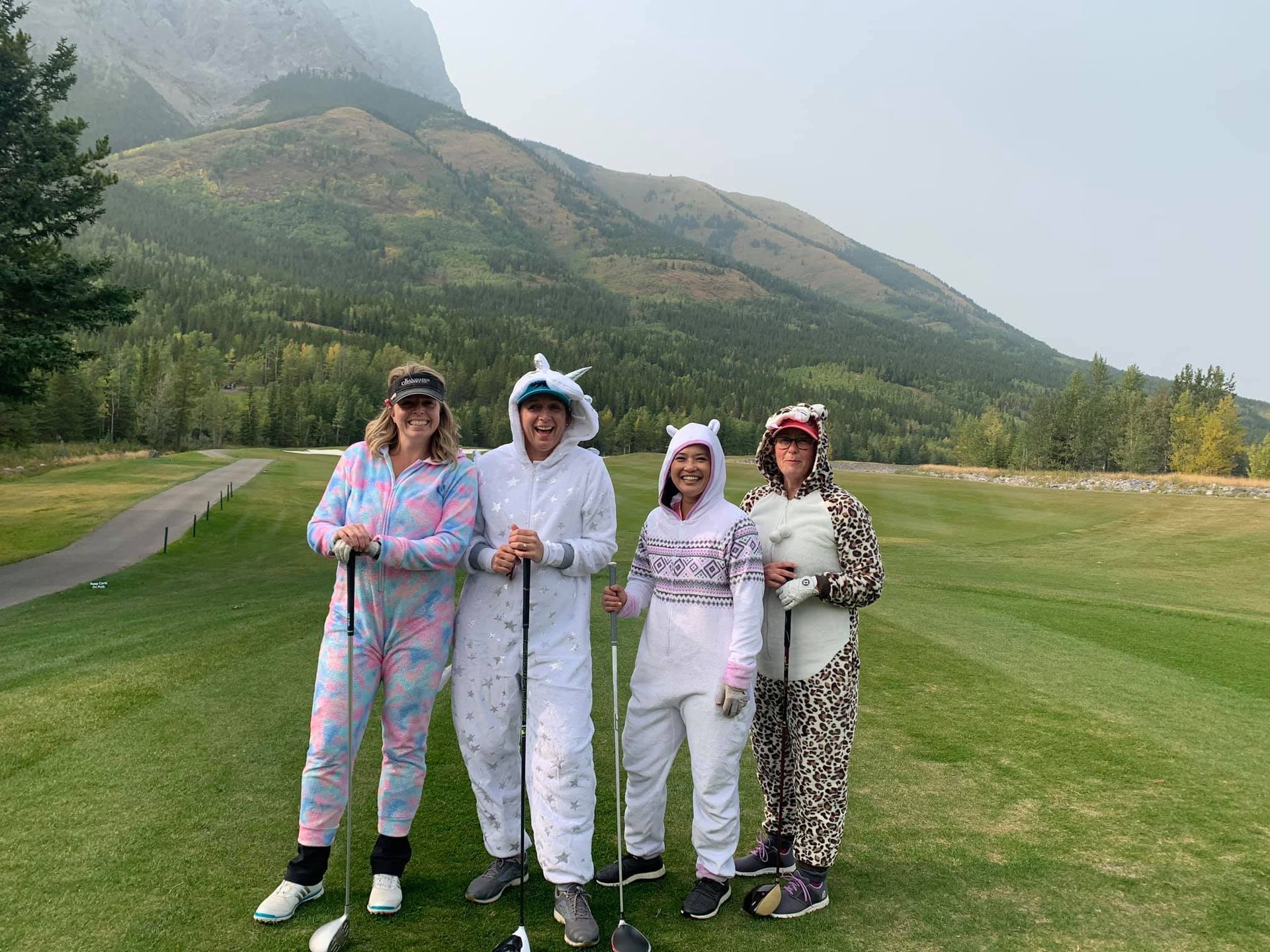 A group of people in pajamas are standing on a golf course holding golf clubs.