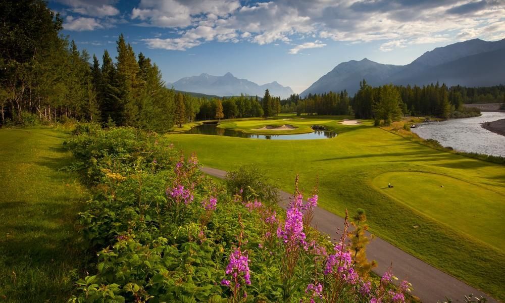 A golf course with a river and mountains in the background