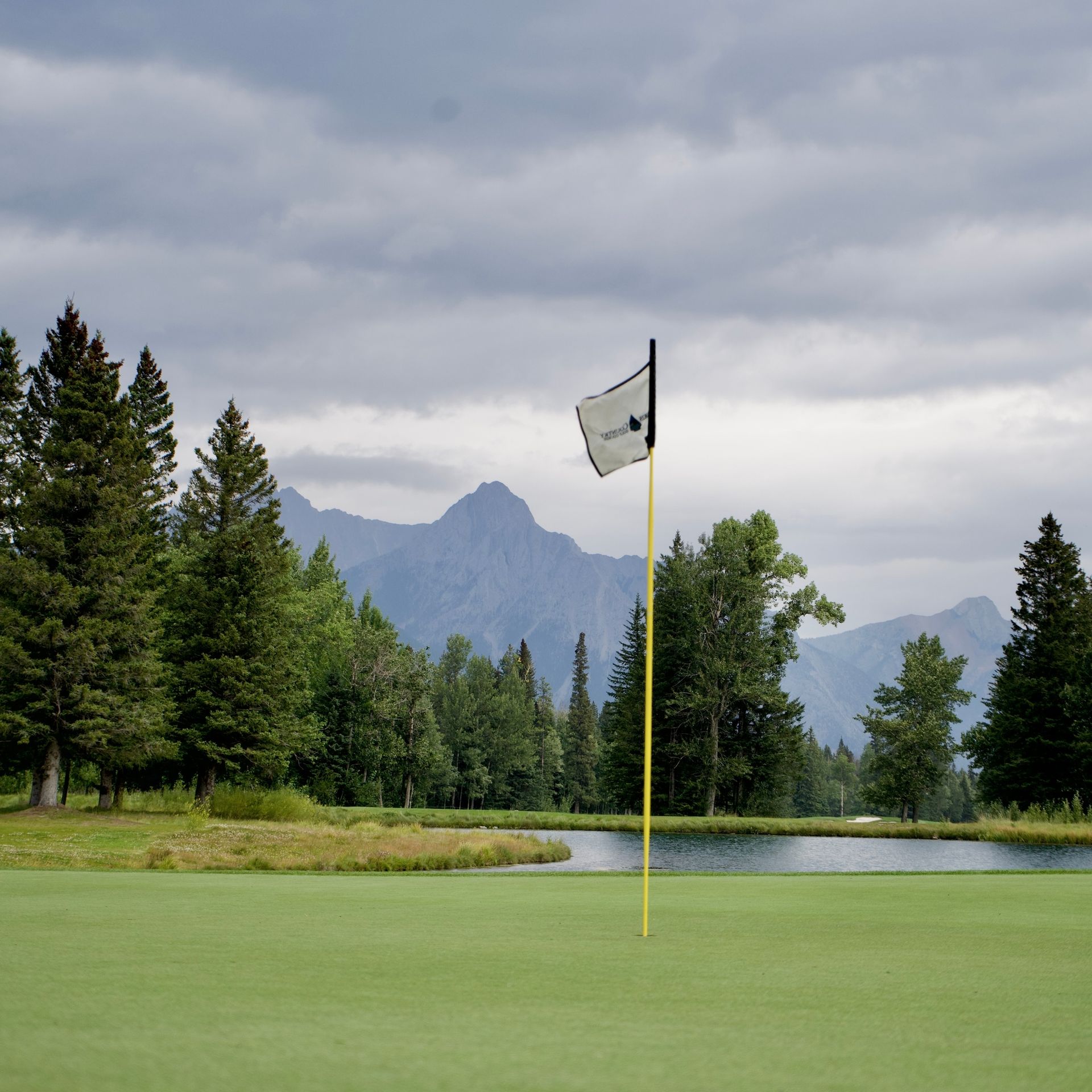 A flag on a golf course with mountains in the background