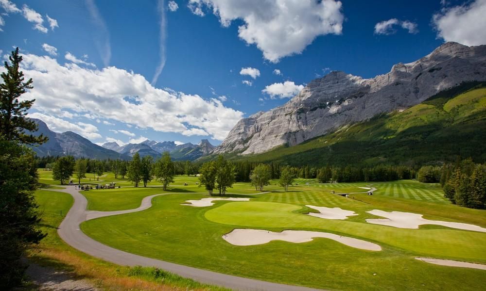 A golf course in the mountains with mountains in the background