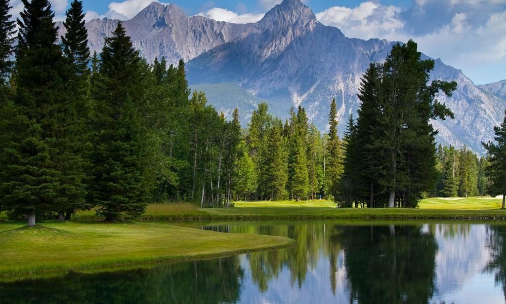 There is a lake in the middle of a forest with mountains in the background.