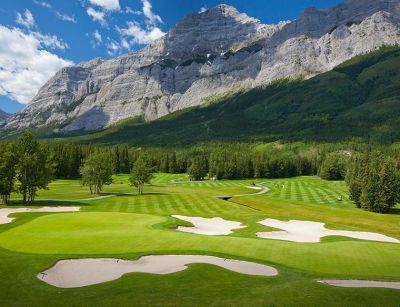 A golf course with mountains in the background and trees in the foreground