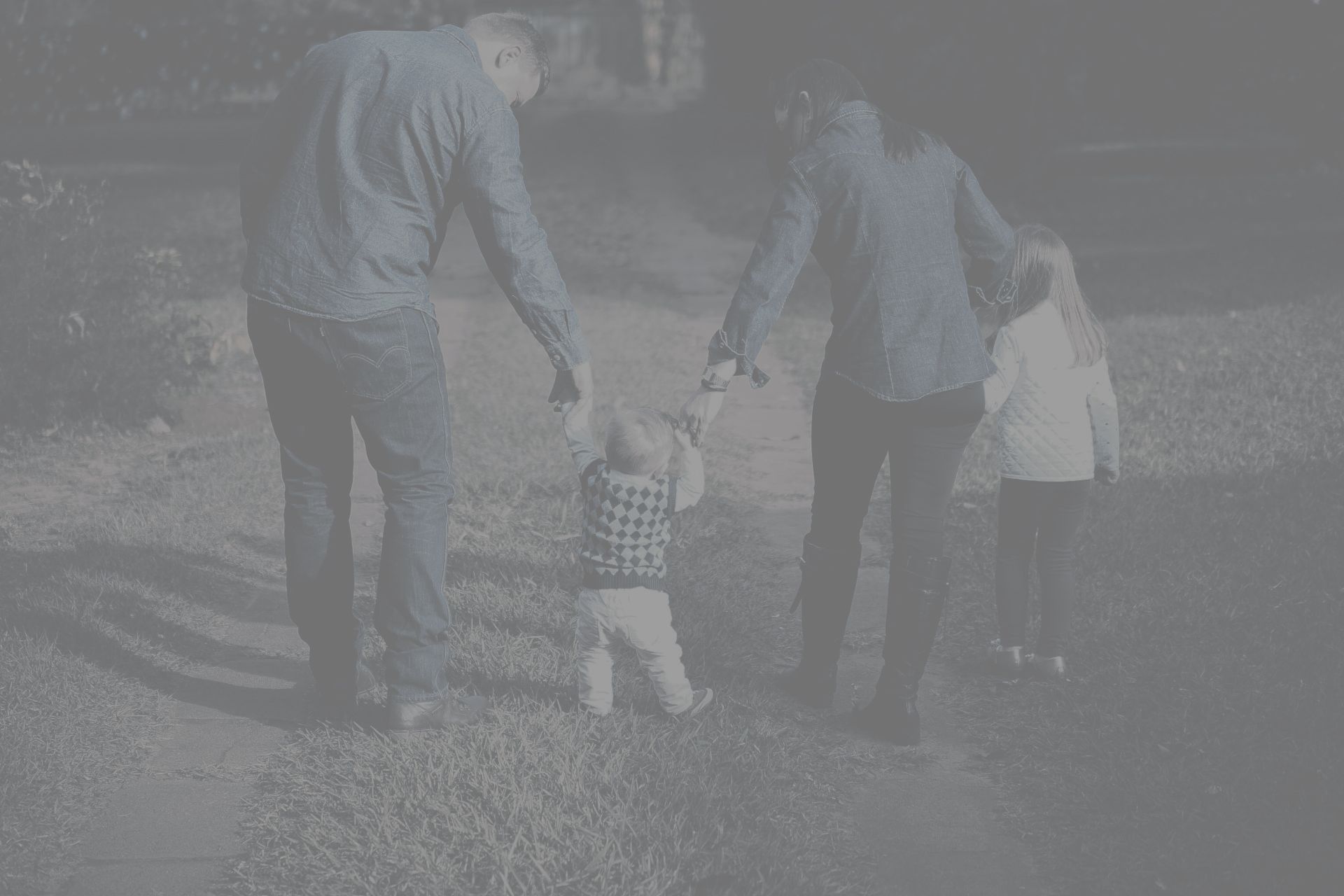 A family is walking down a path holding hands.