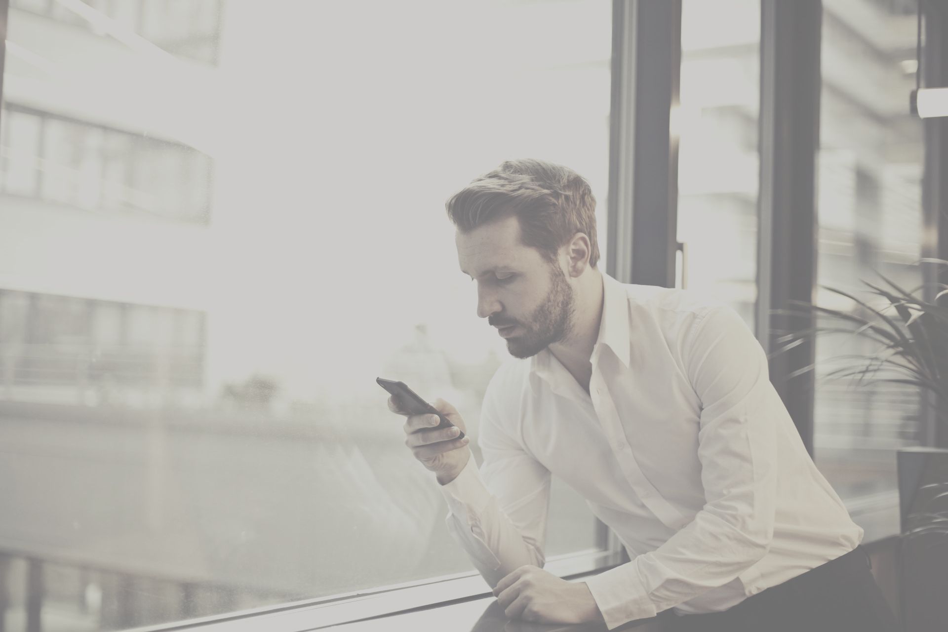 A man is sitting at a table looking at his cell phone.