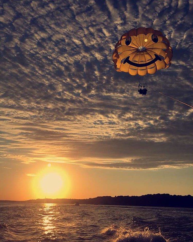 Sunset over water with a parachute rider gliding above the waves