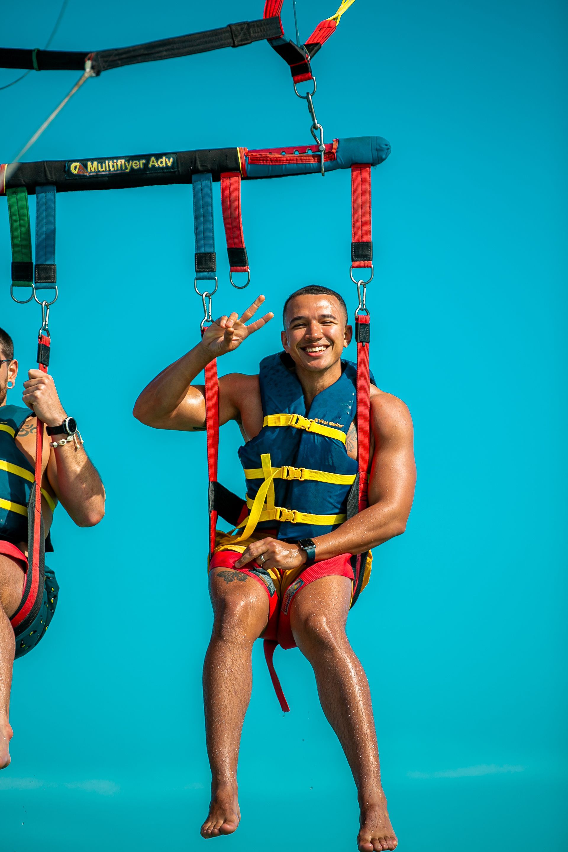 Person smiling on a parasailing harness against a bright blue sky