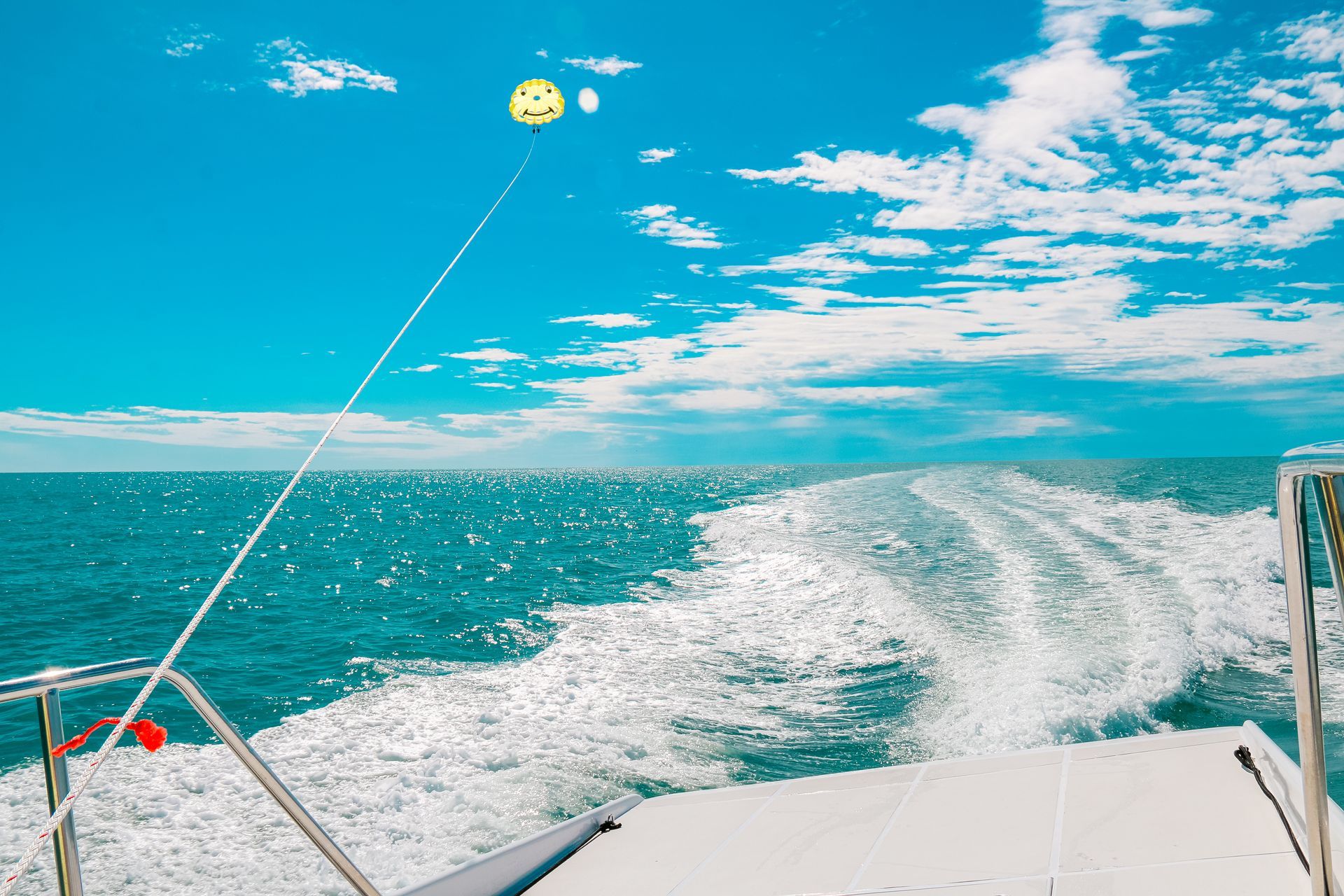 View from a boat over turquoise ocean with a foamy wake under a bright blue sky