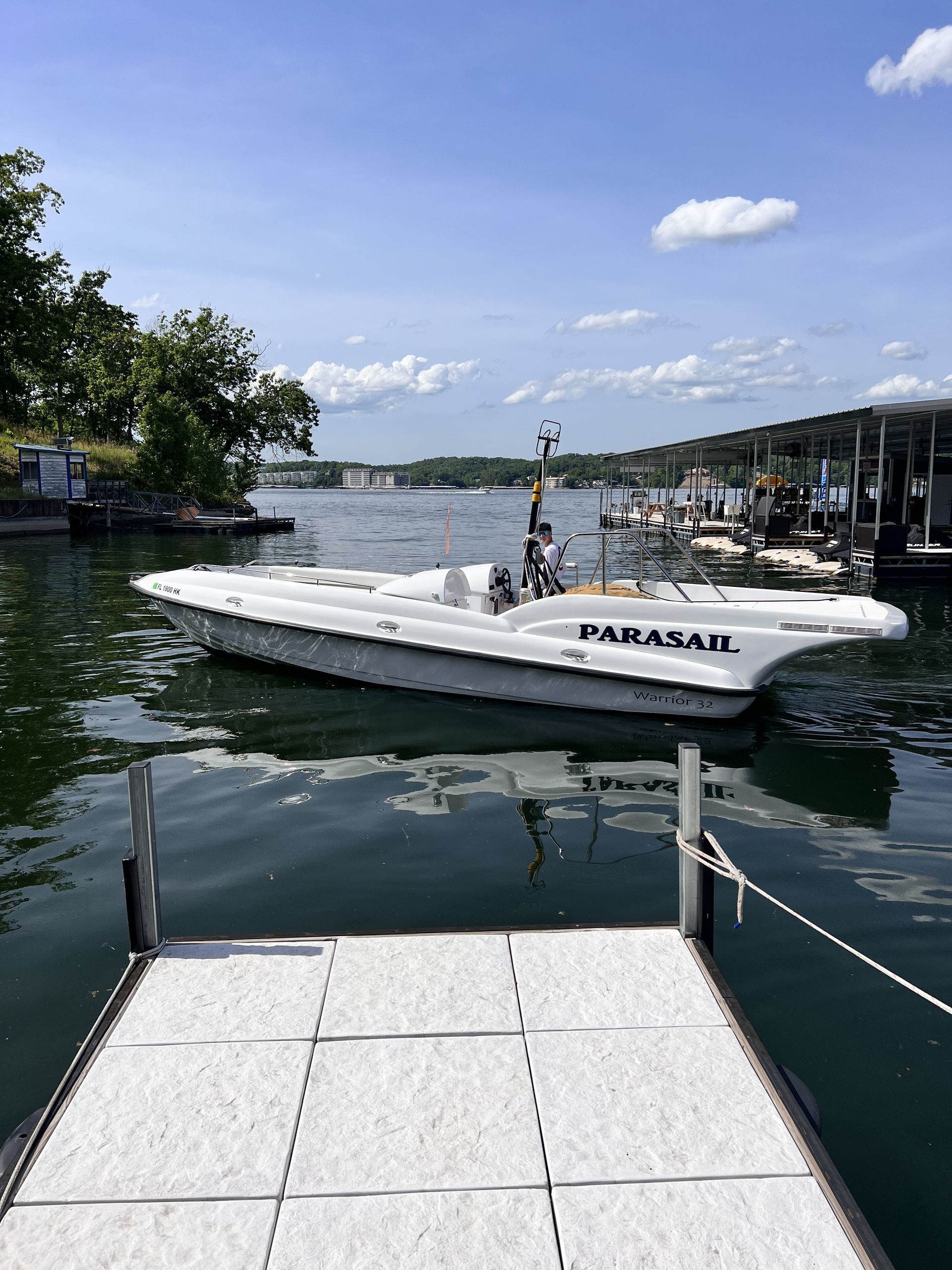 White motorboat on calm marina water beside a dock under a sunny blue sky