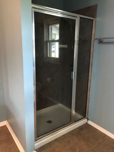 A bathroom with a sliding glass shower door and a window.