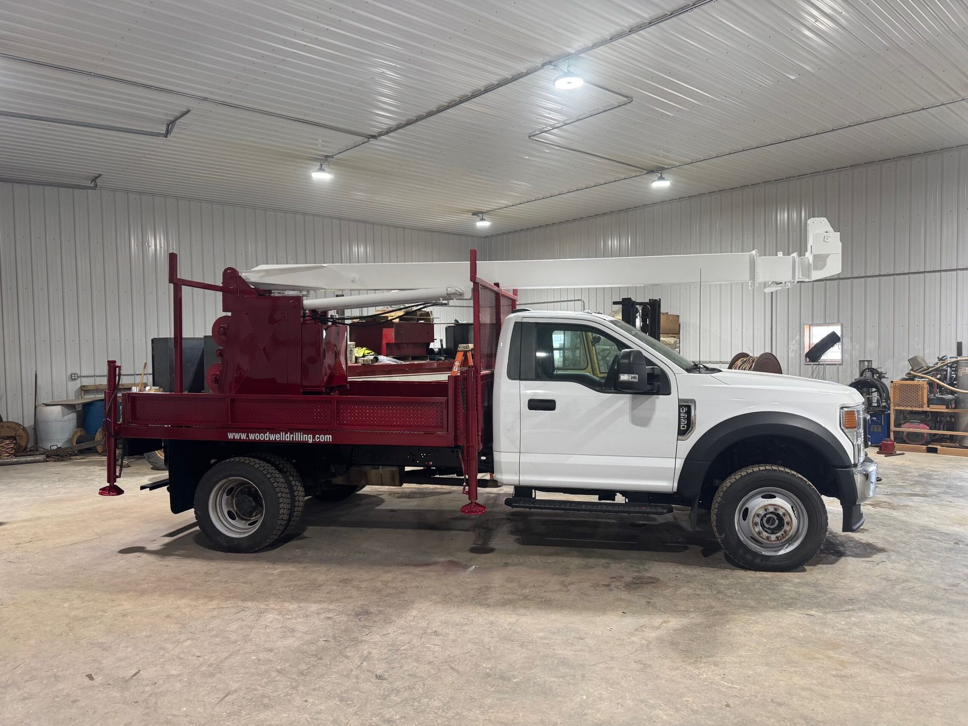 White dump truck with red flatbed parked inside a garage or workshop