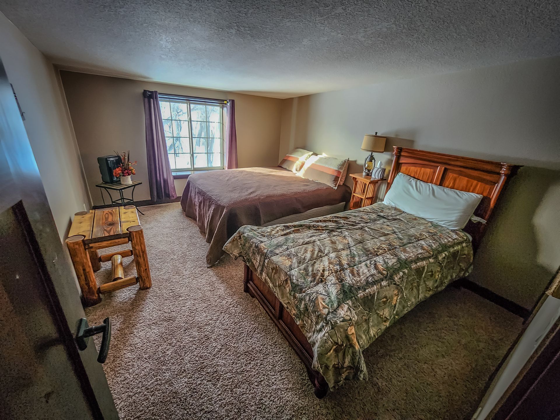 A hotel room with two beds , a table and a window.