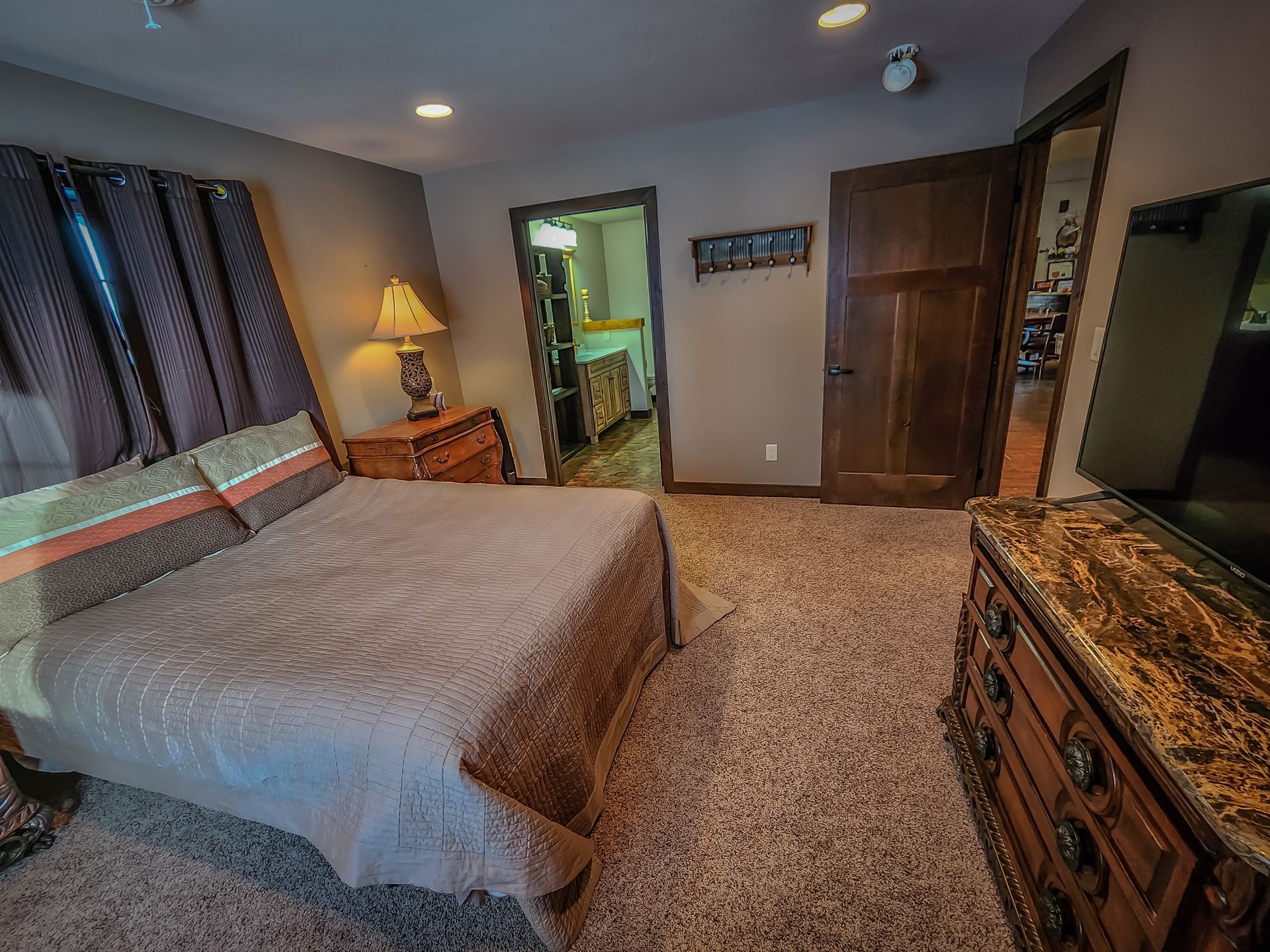 A bedroom with a king size bed , dresser , and television.