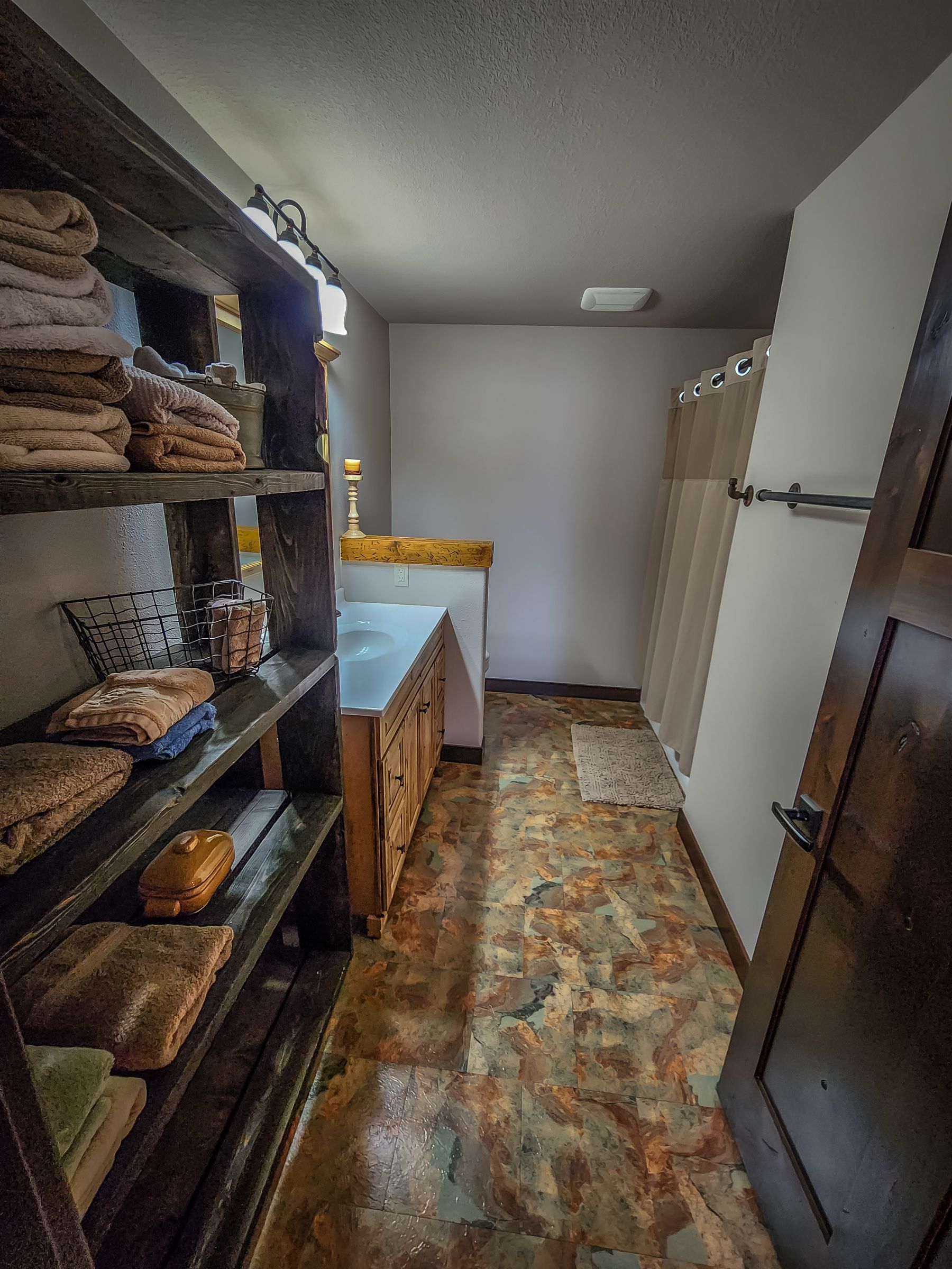 A bathroom with a sink , shelves , and a shower.