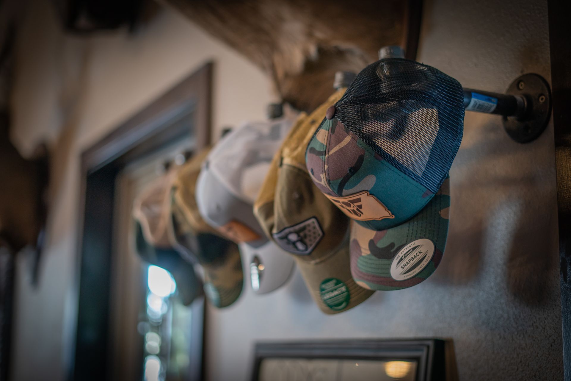 A bunch of hats are hanging on a wall.