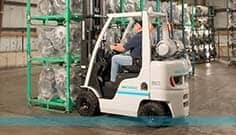 Forklifts — Worker Driving A White Forklift Inside The Warehouse In Manorville, NY