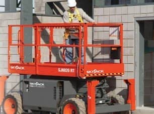 Forklifts — Worker Standing Above The Rough Terrain Scissor Lifts In Manorville, NY