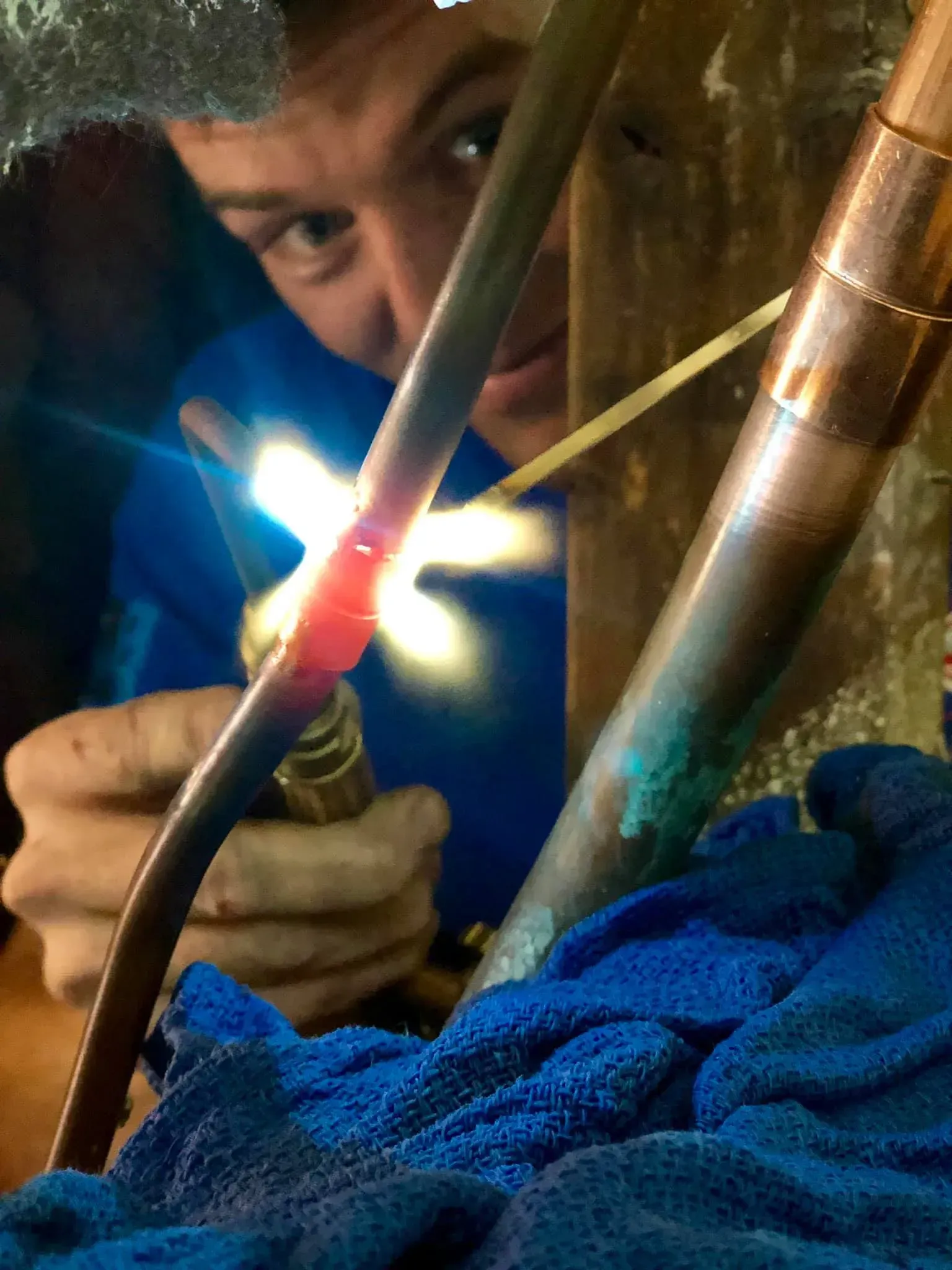 A man is welding copper pipes with a torch