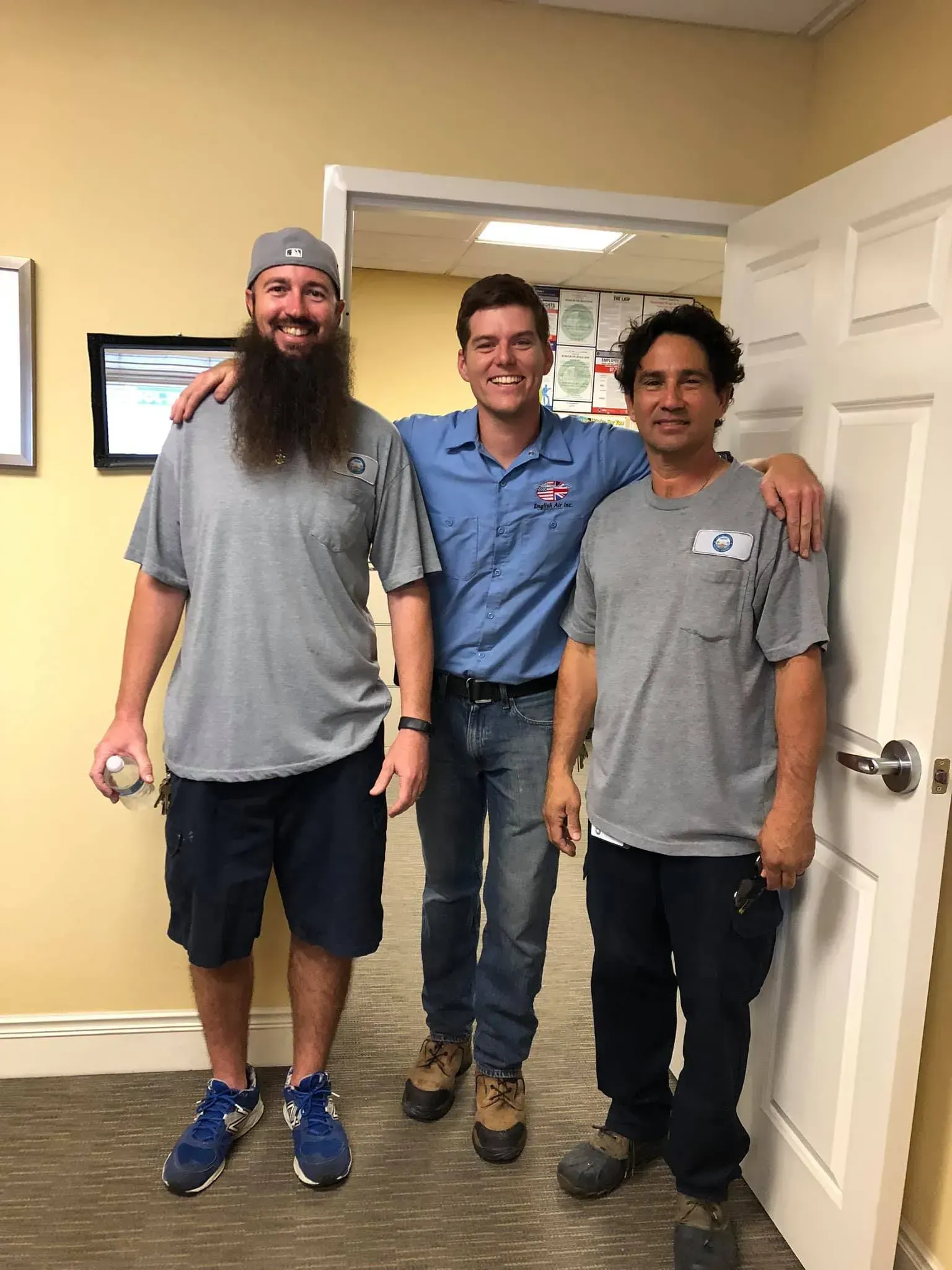 Three men are posing for a picture in front of a door.