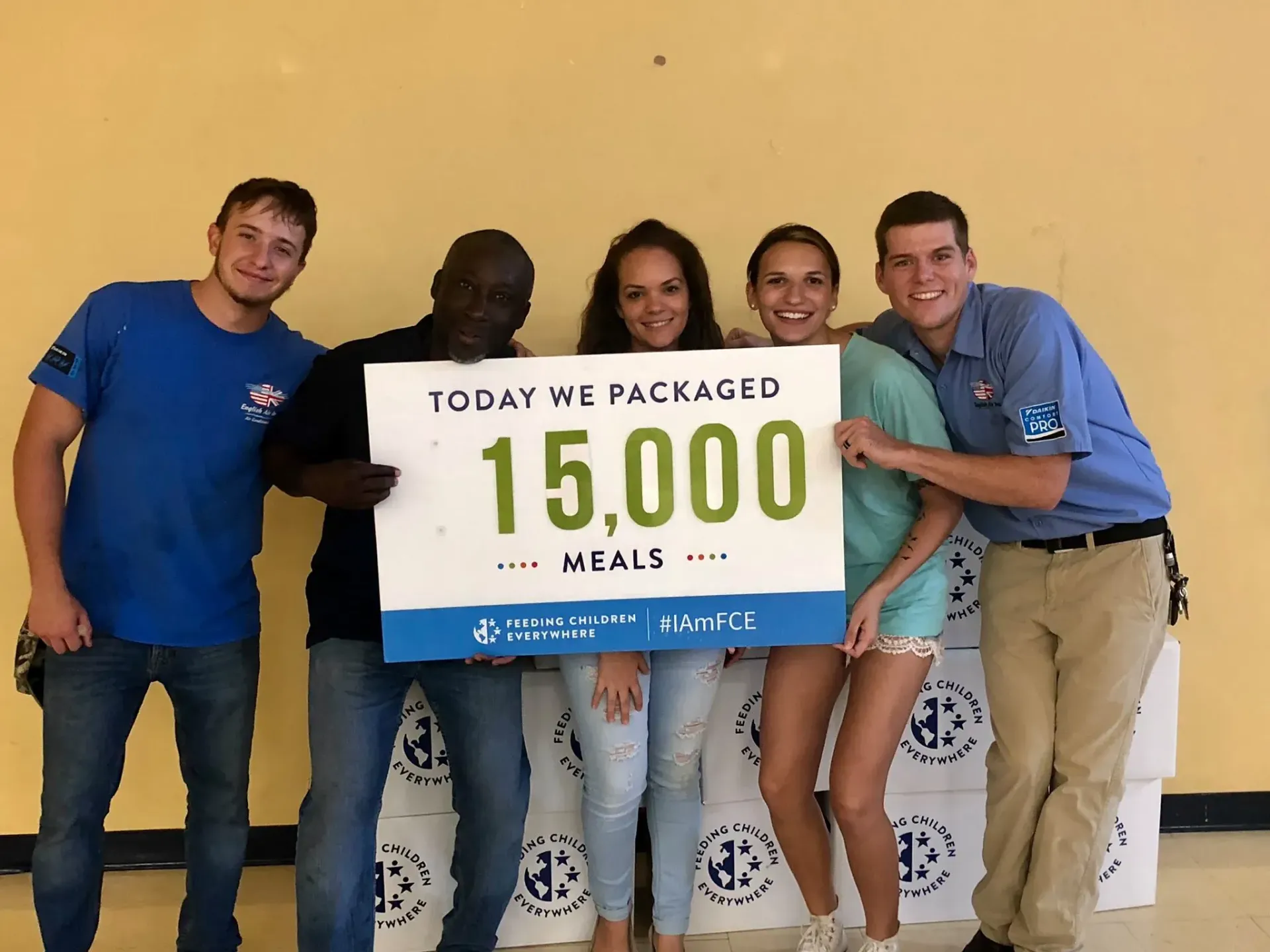 A group of people holding a sign that says today we packaged 15,000 meals