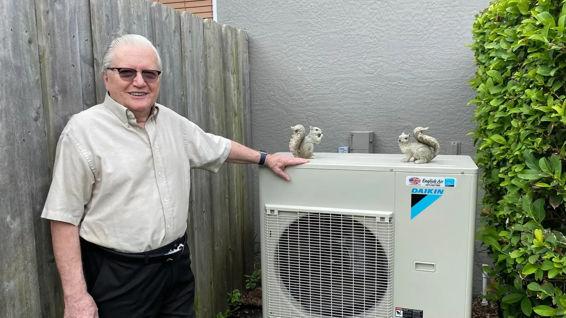 A man is standing next to a large air conditioner.