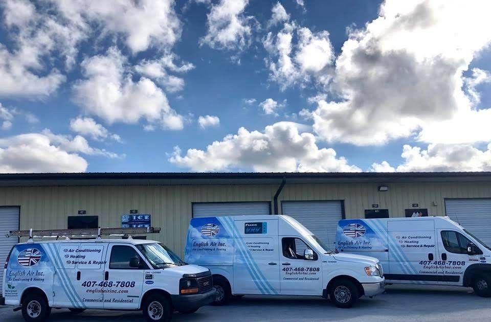 Three white vans are parked in front of a building