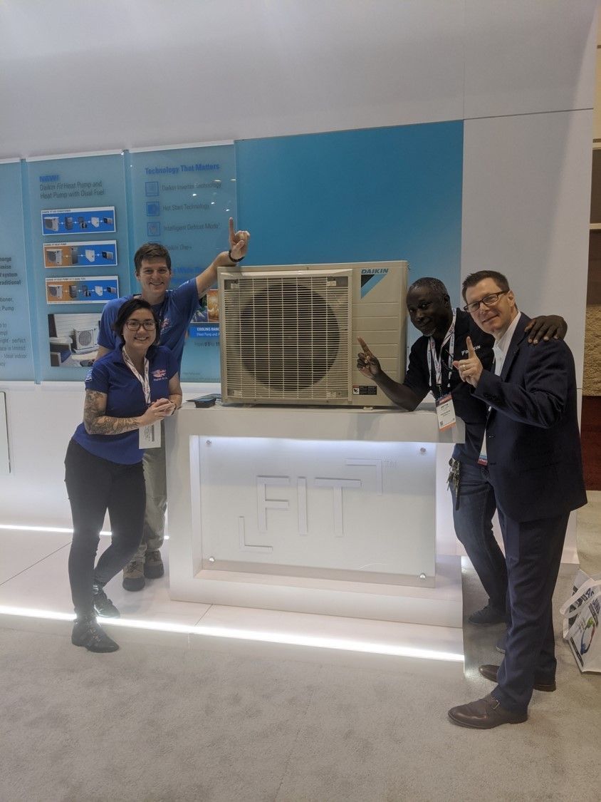 A group of people standing around a large air conditioner