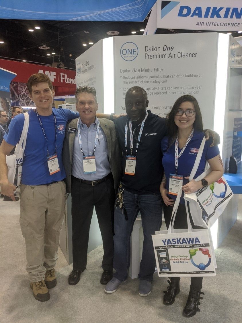 A group of people posing for a picture at a daikin booth