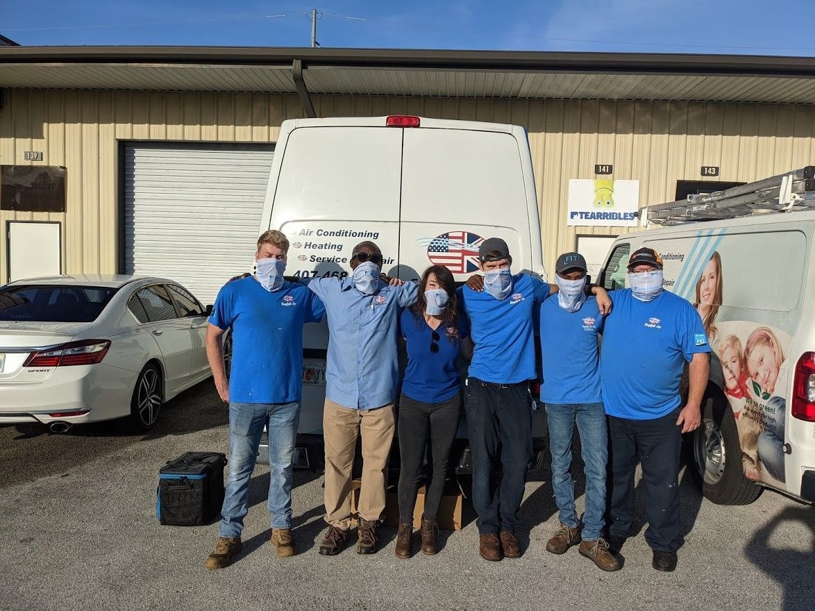A group of people wearing face masks are posing for a picture in front of a building.