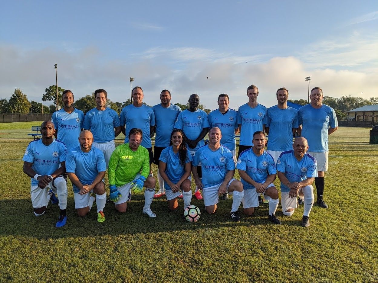 A group of men are posing for a picture on a soccer field.