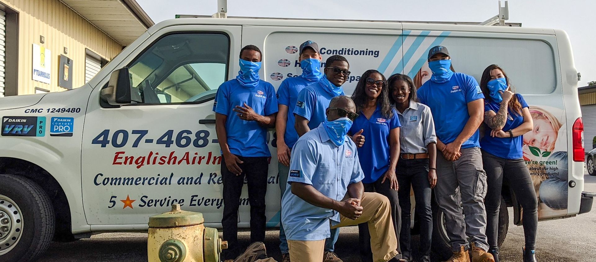 A group of people wearing face masks are posing for a picture in front of a van.