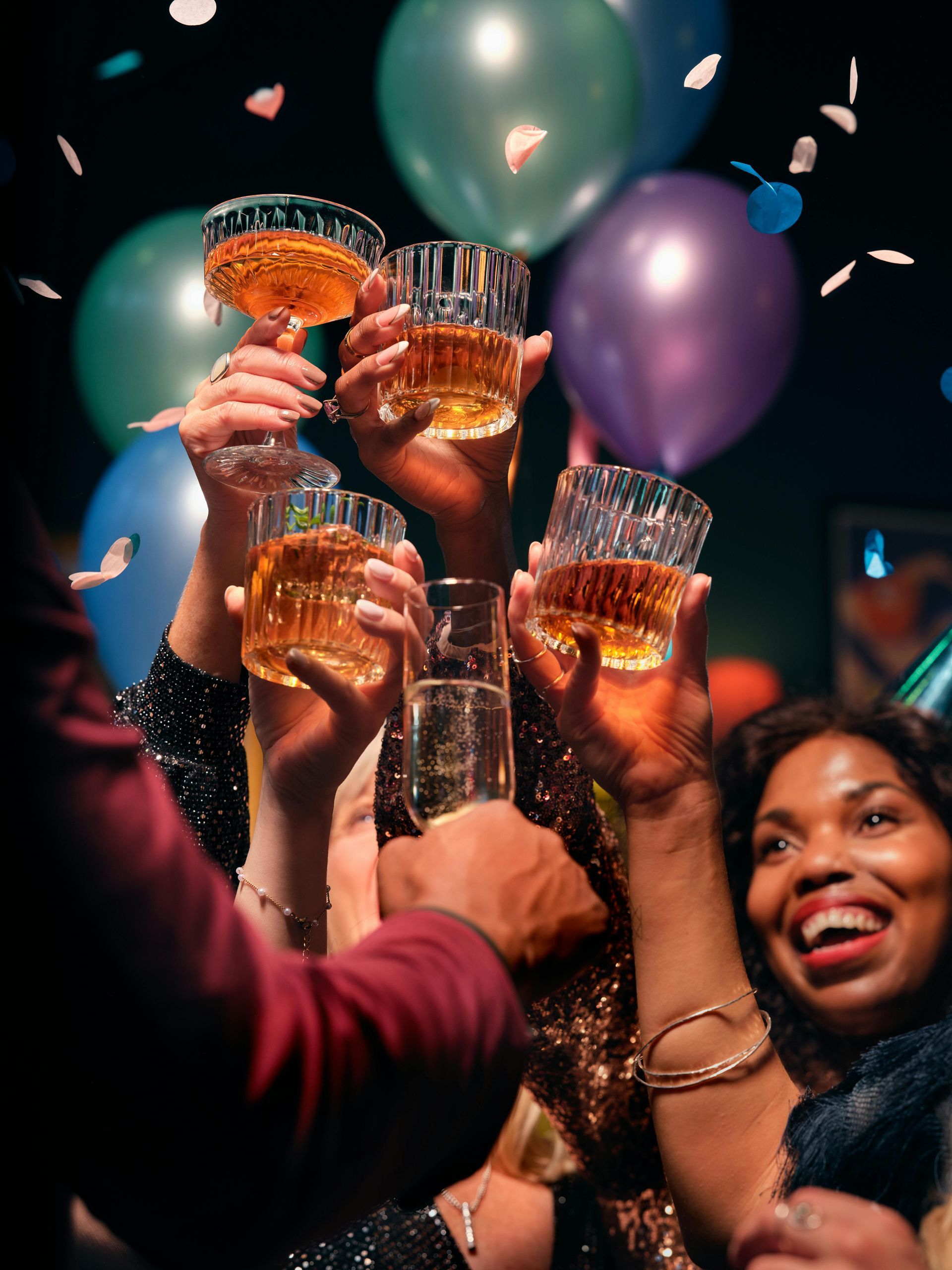 A group of people are raising their glasses in the air at a party.