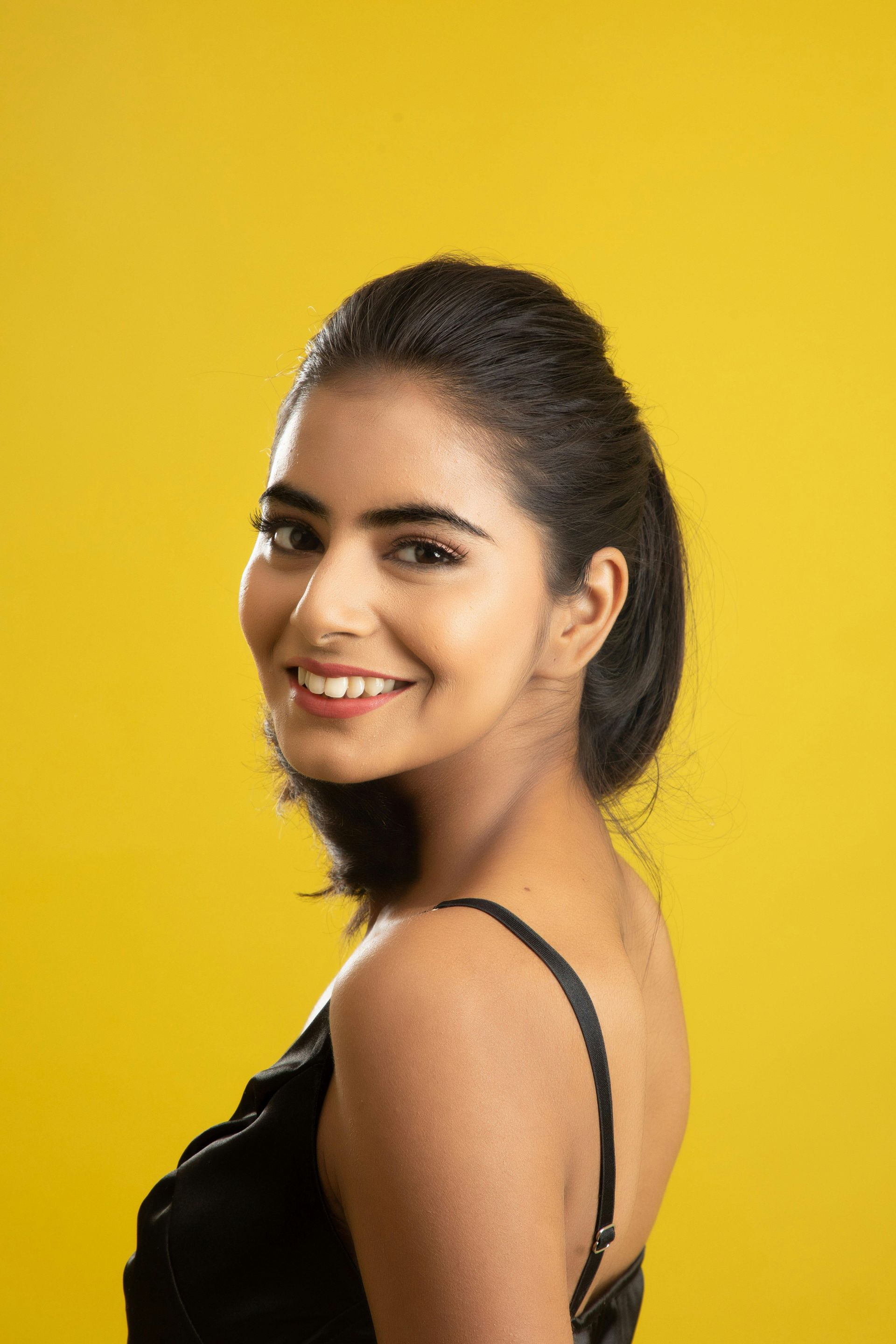 A woman in a black top is smiling and looking over her shoulder.