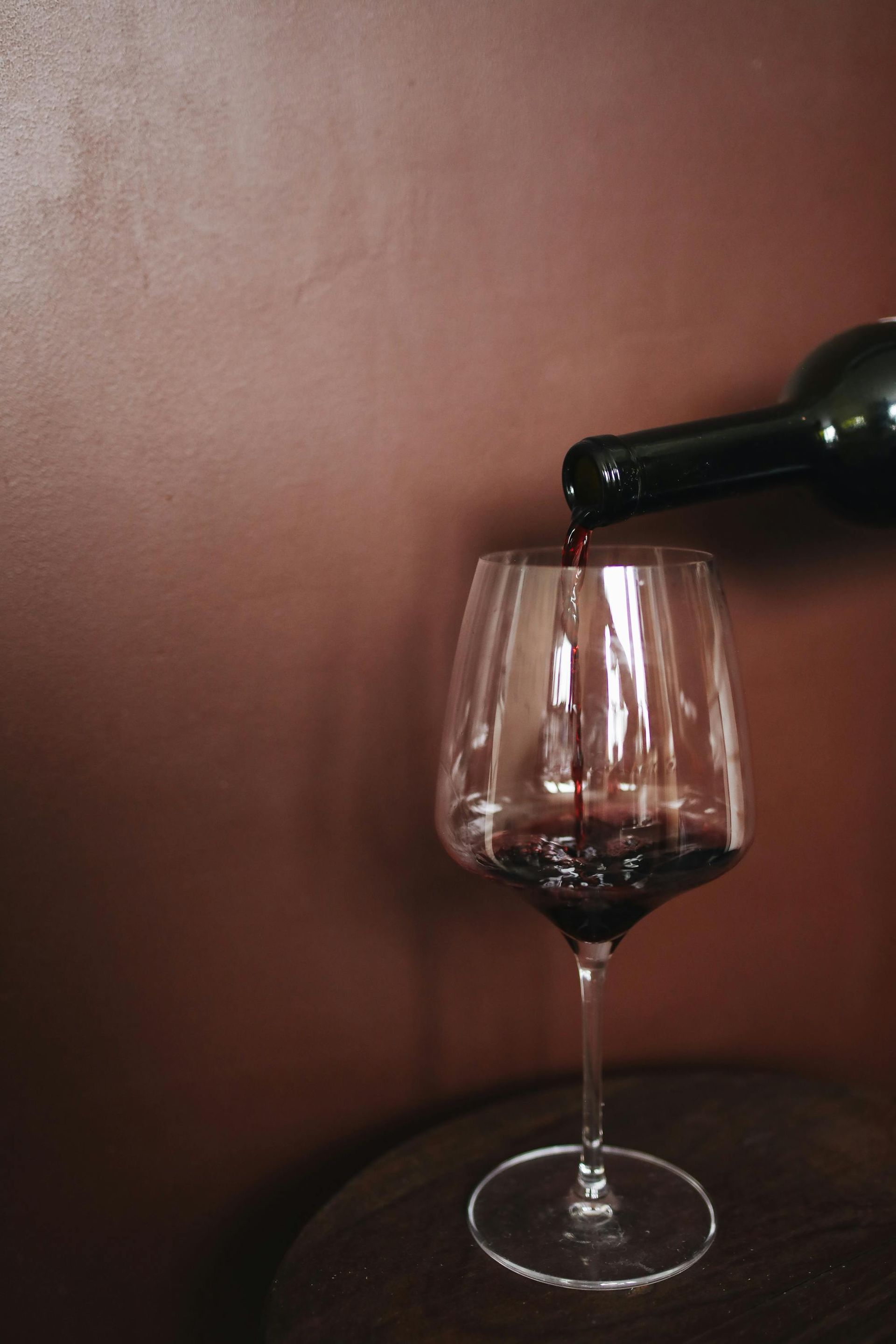 A bottle of wine is being poured into a glass on a table.