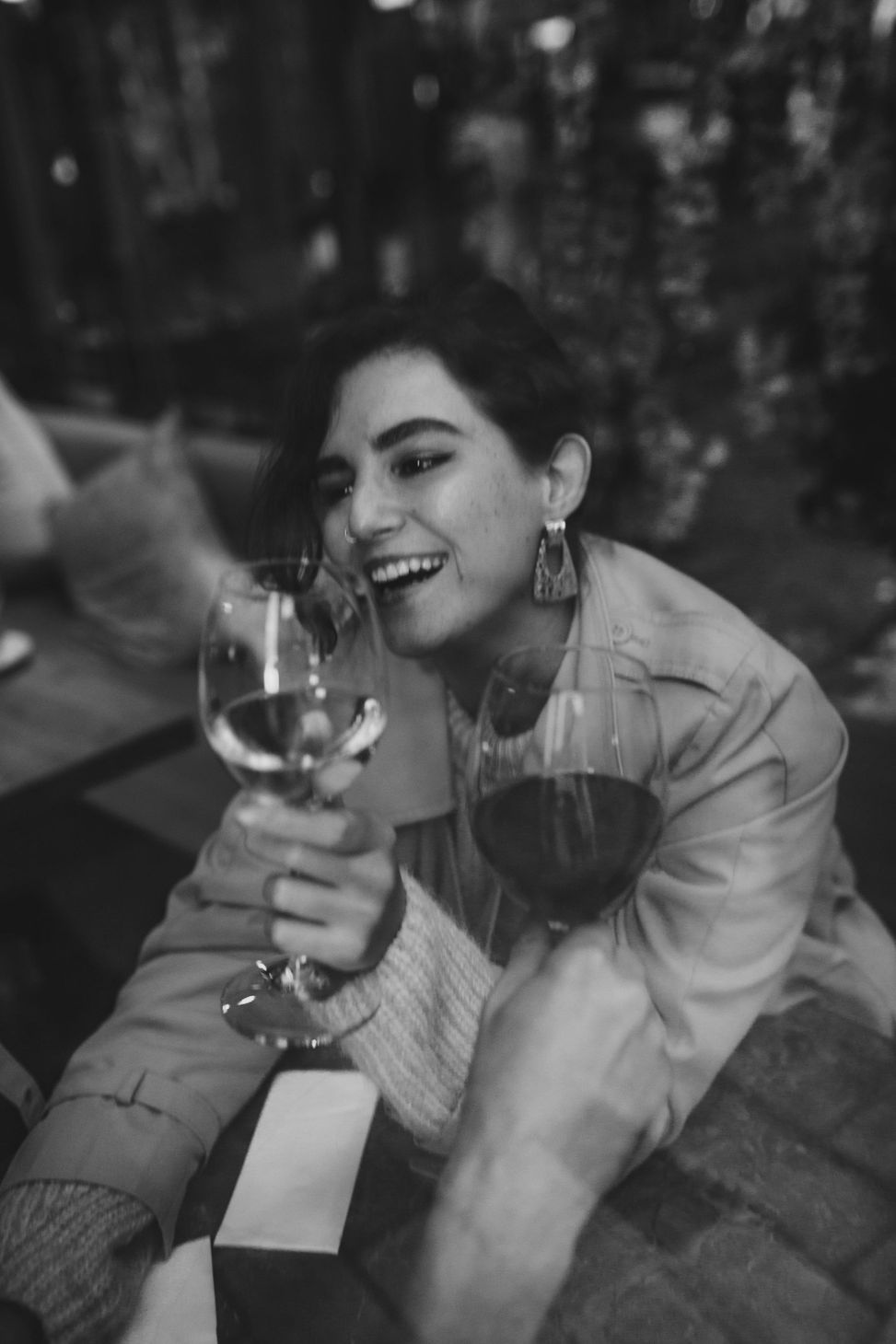 A woman is holding a glass of wine and smiling in a black and white photo.