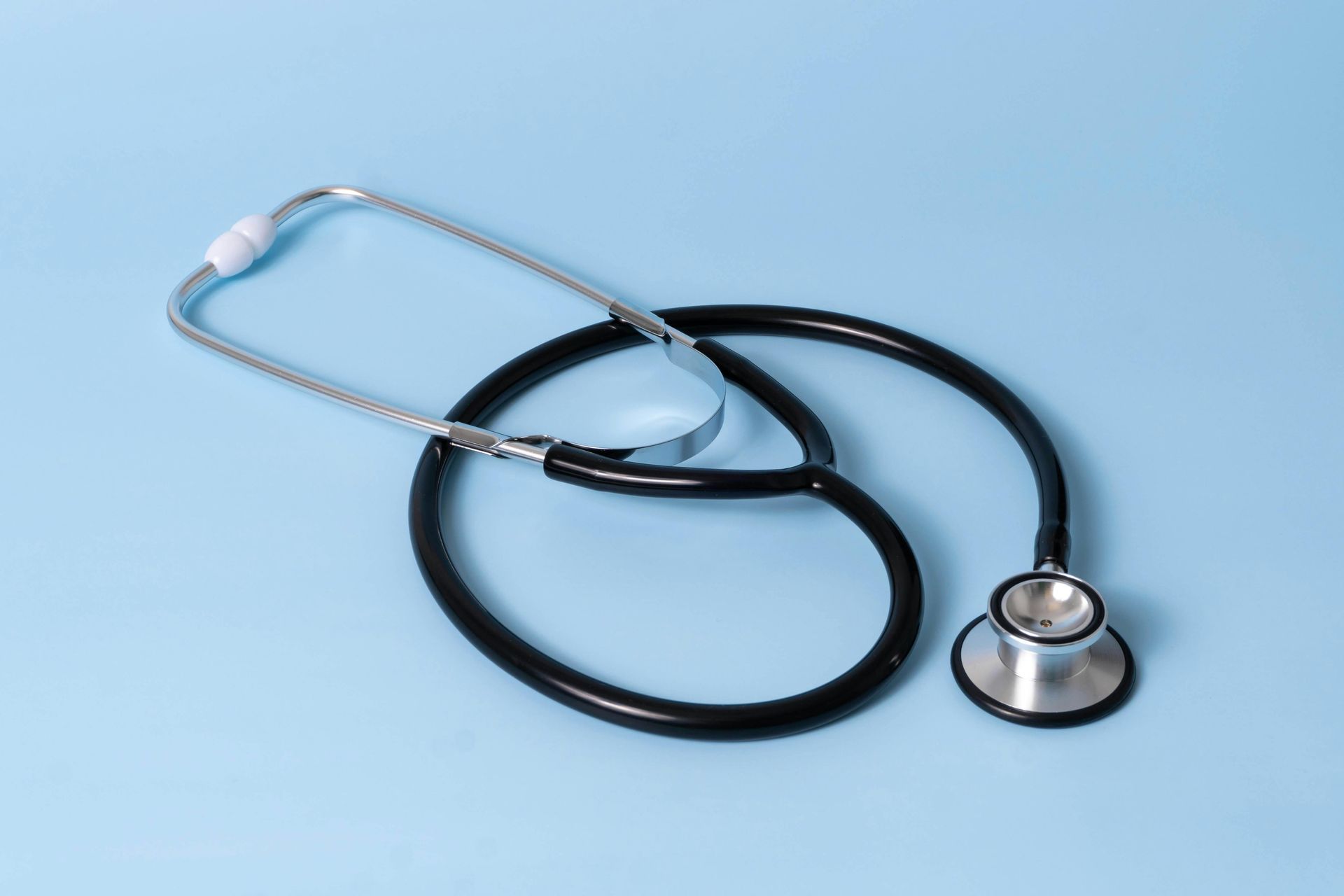 Black stethoscope on a blue surface; medical device used by doctors to listen to sounds within the body.