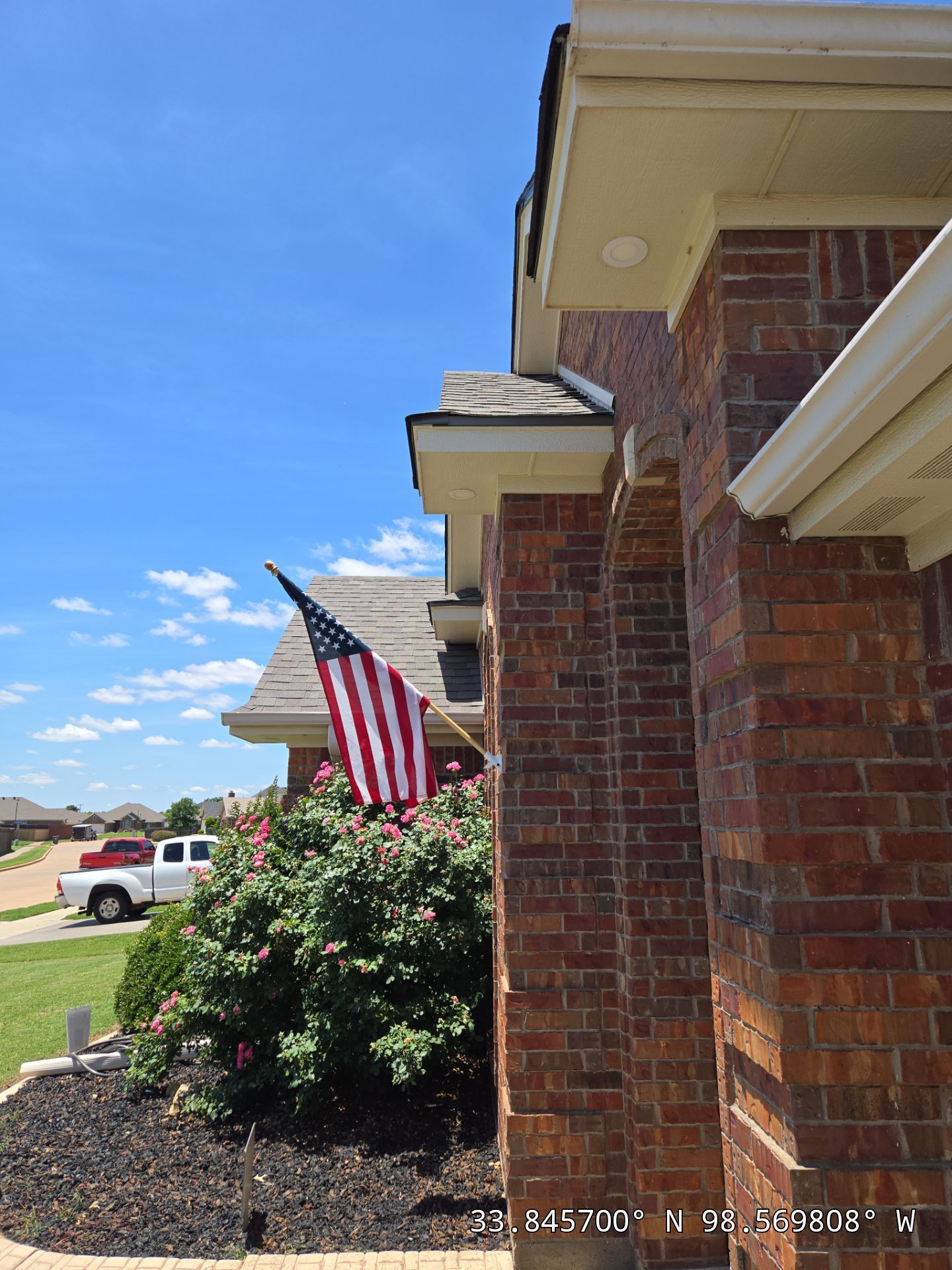 An american flag is flying in front of a brick house