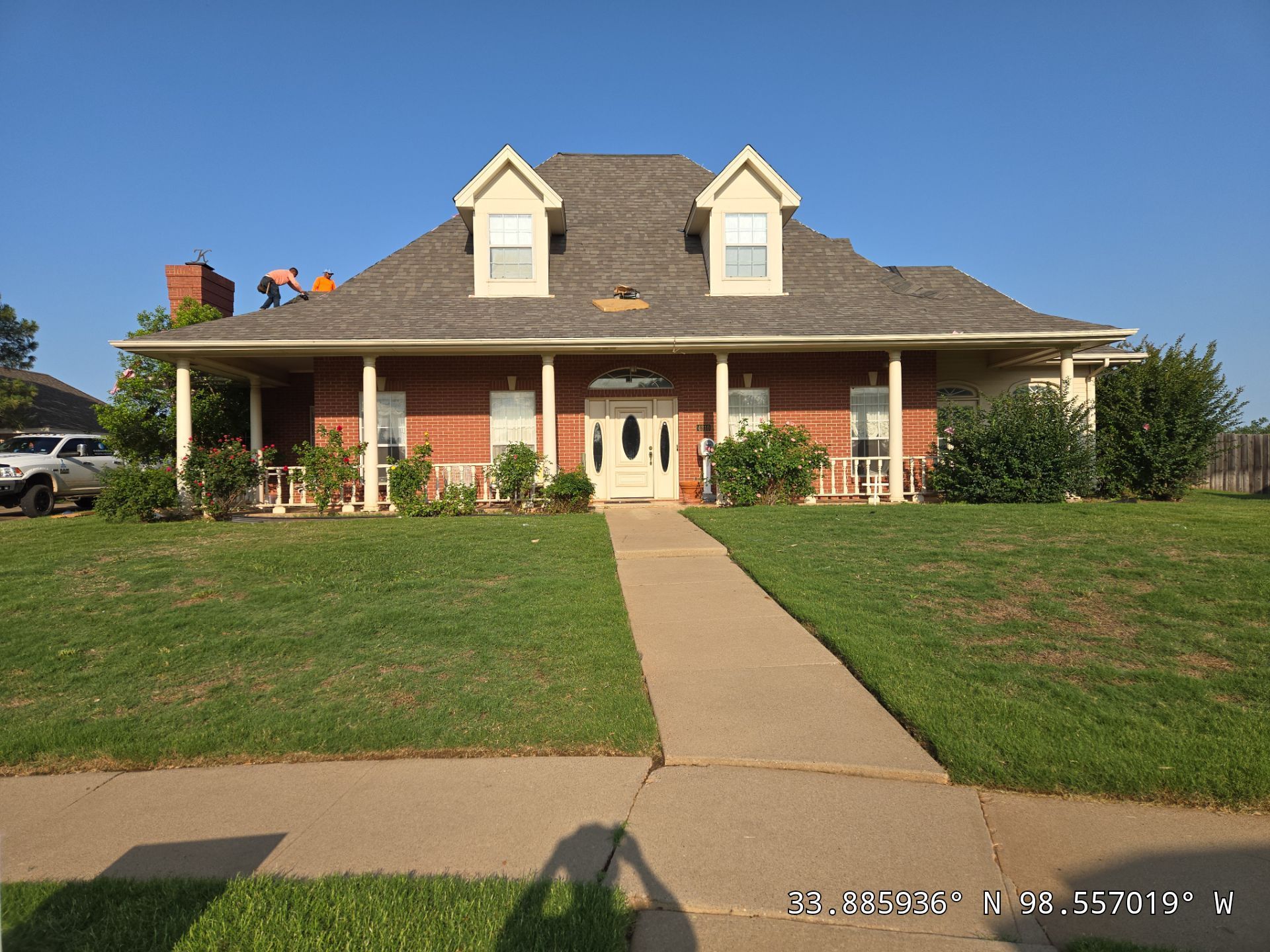 A large brick house with a gray roof and white trim