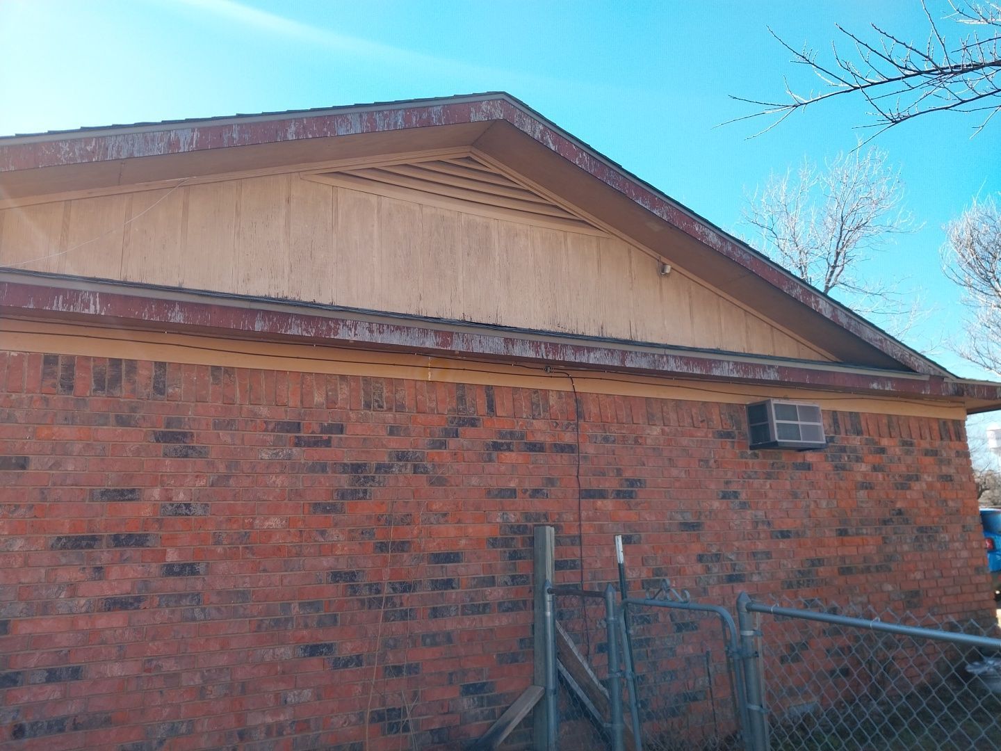 A brick building with a wooden roof and a fence in front of it.