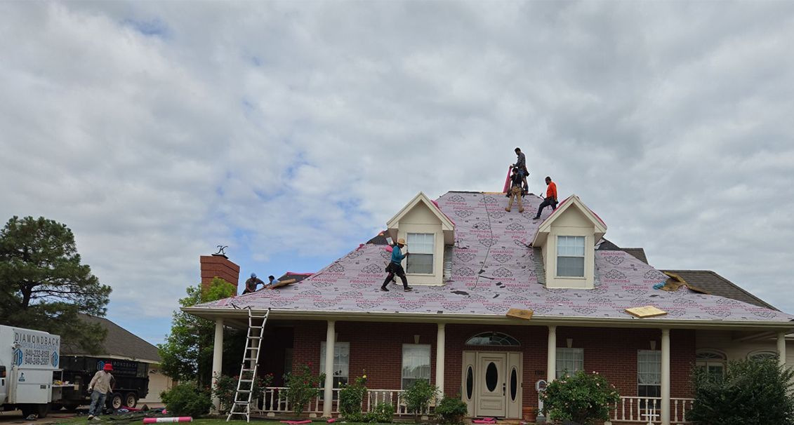 A group of people are working on the roof of a house.