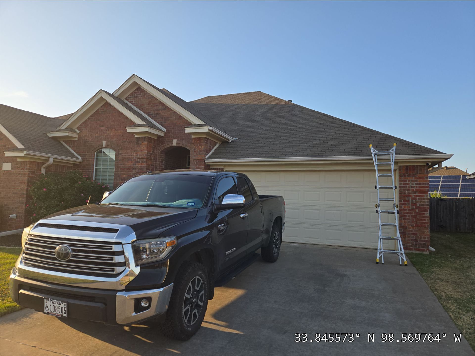 A black truck is parked in front of a brick house.