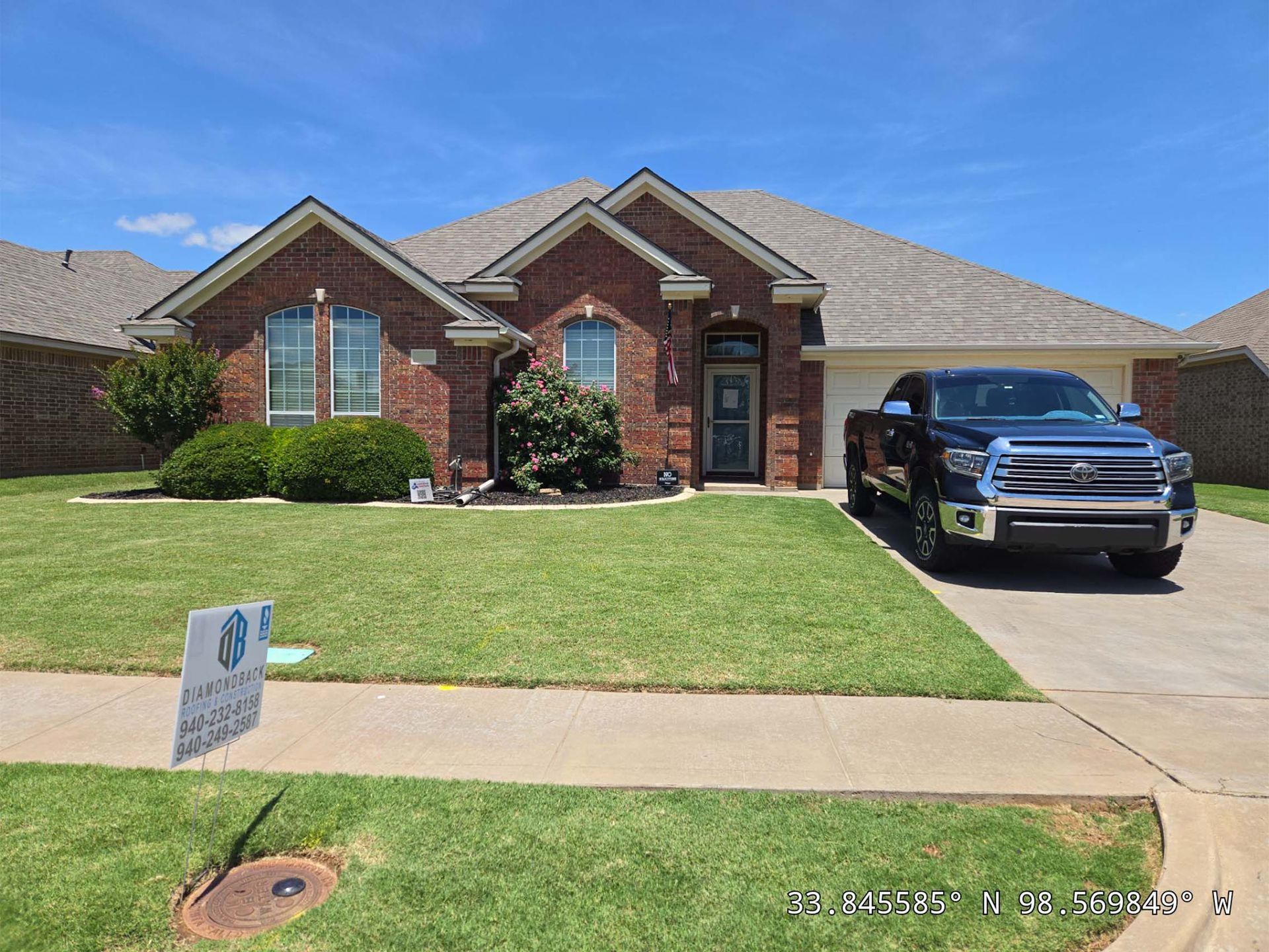 A truck is parked in front of a brick house.