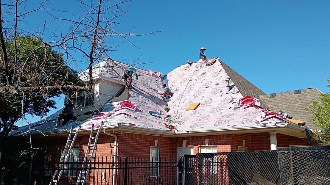 A brick house is being remodeled with a new roof.