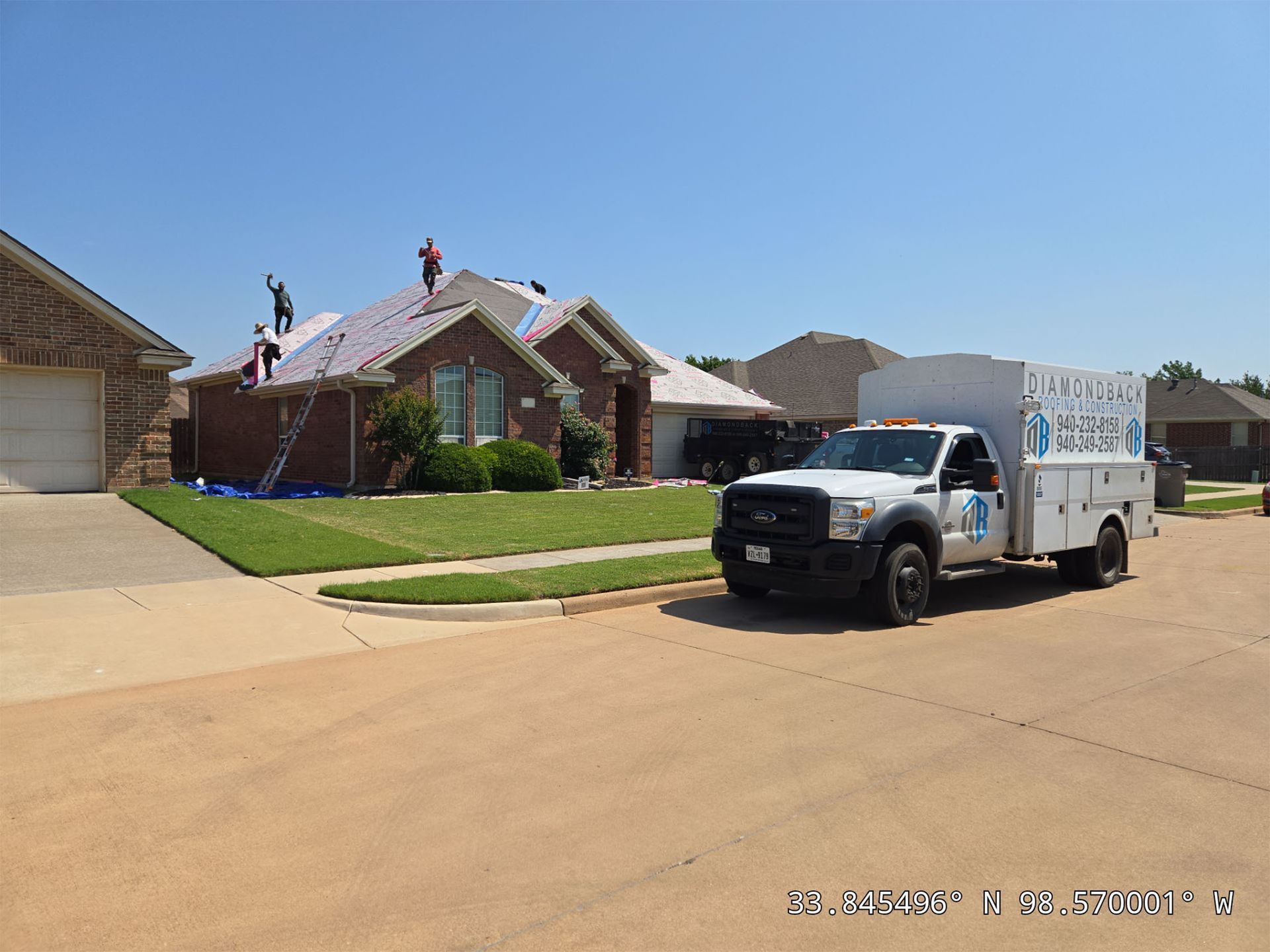 A white truck is parked in front of a brick house